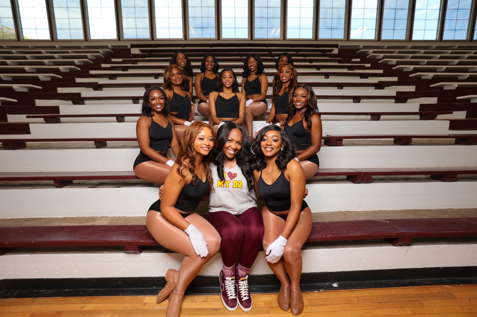 Coach Granger sits in Frank Lewis Gym with Dancin' Divas