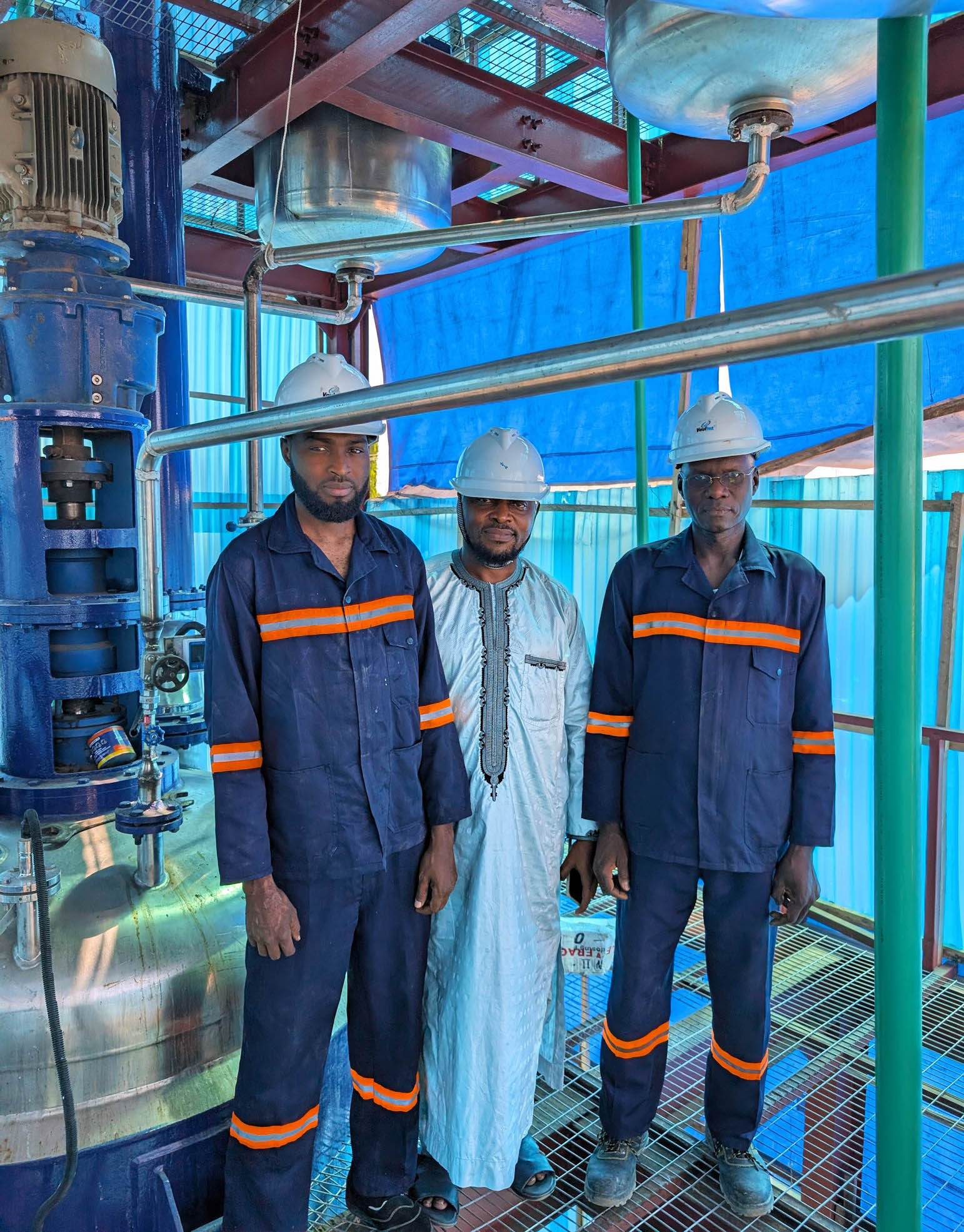 Jafar and two workers wear hard hats at his company in Nigeria