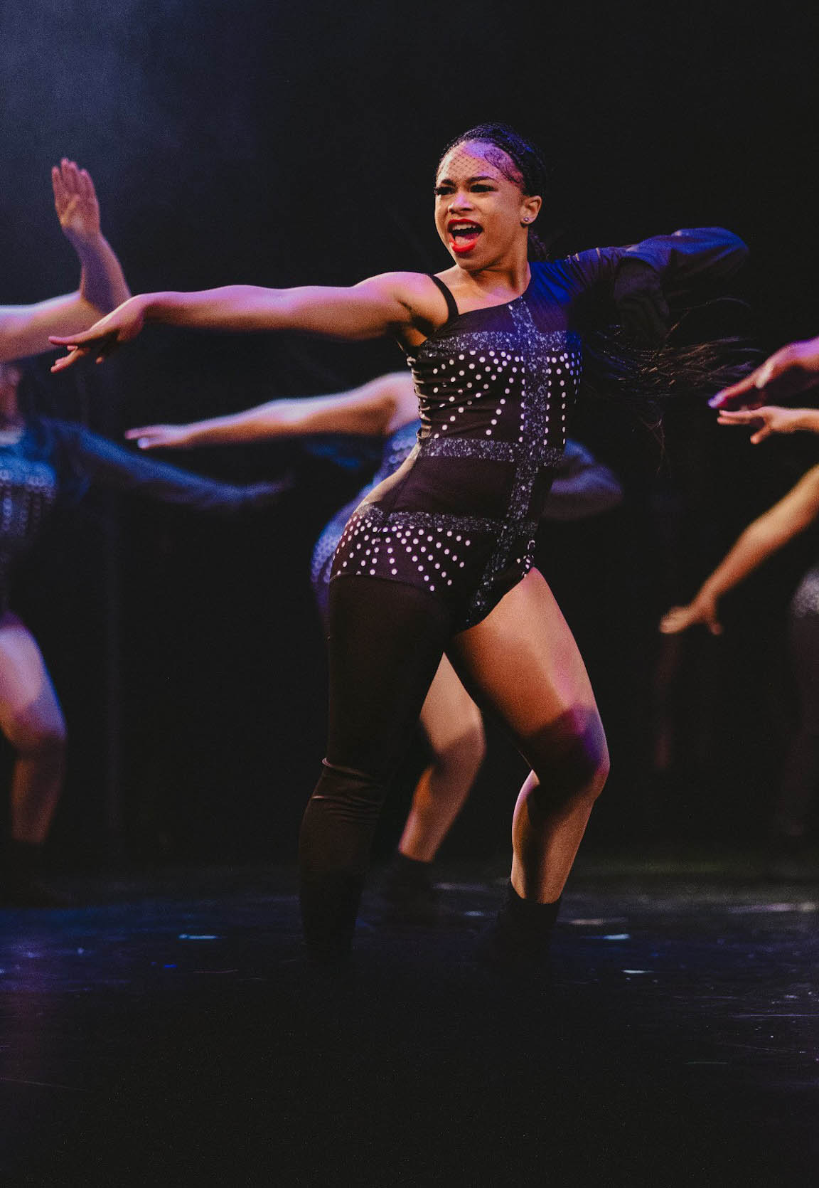 Londyn Phillips dancing on stage with other dancers behind her