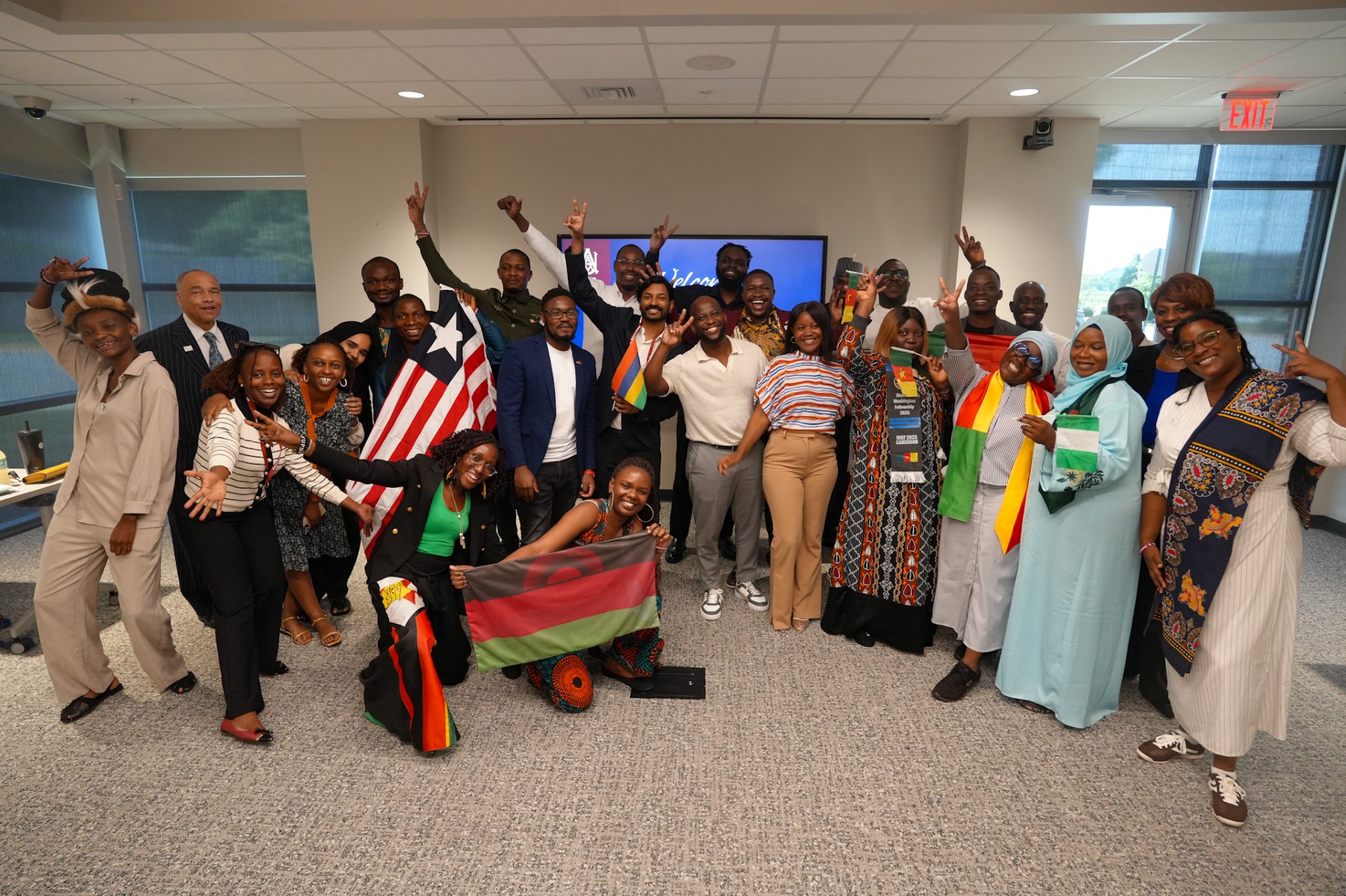2025 Mandela Fellows take a fun group photo, many holding the flags of their country