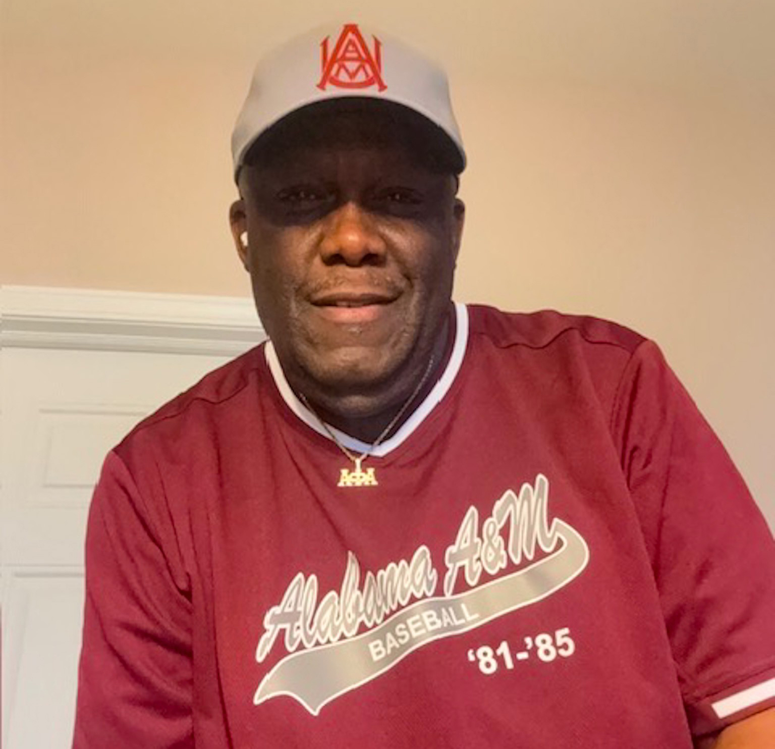 Marshall wearing AAMU baseball jersey and hat in his home