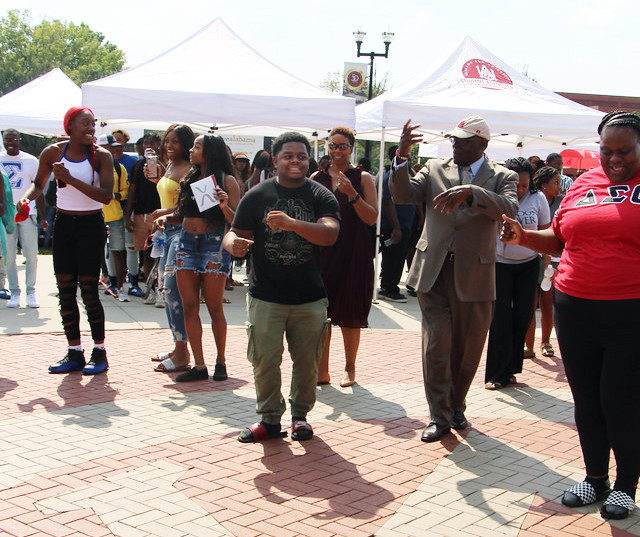 Students dancing with President Hugine on The Quad