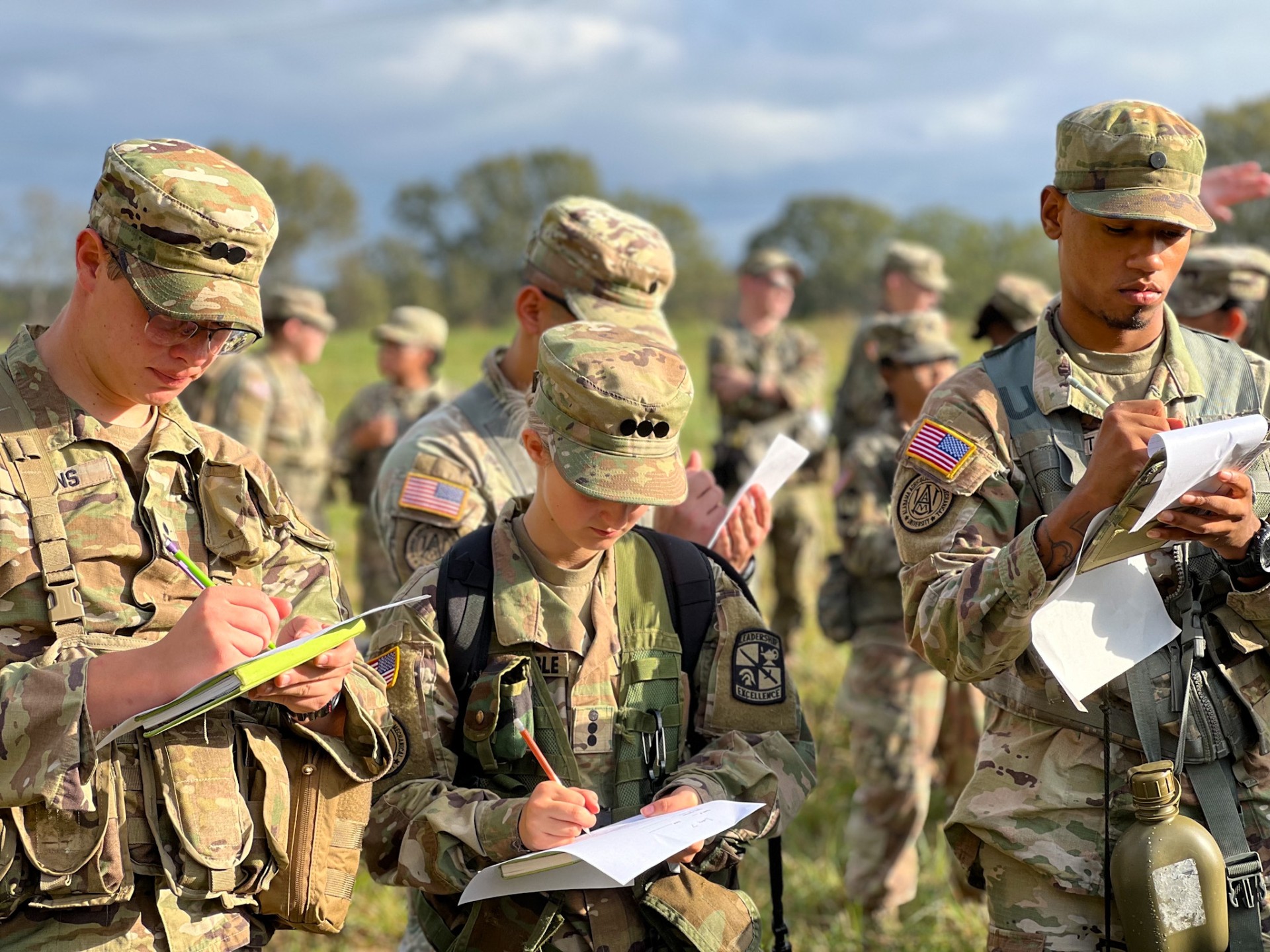 Tight shot of 4 cadets looking at maps with 6 cadets blurred in the background