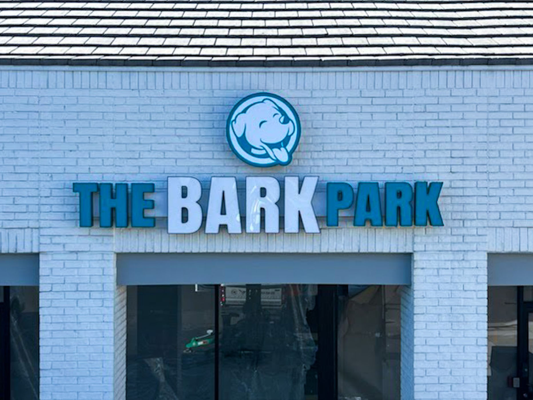 Business sign that reads 'The Bark Park' with a dog's head on top