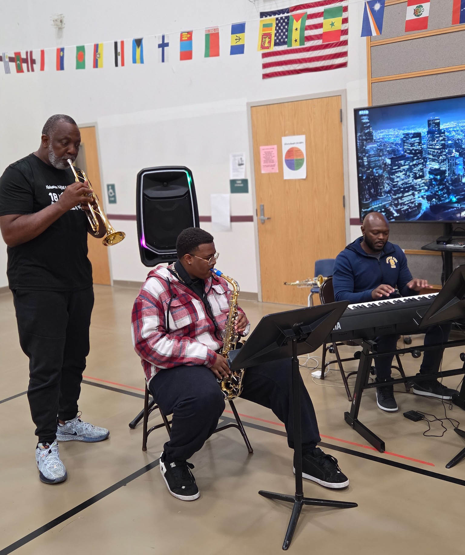 Wright playing instrument next to seated student and colleague at the piano