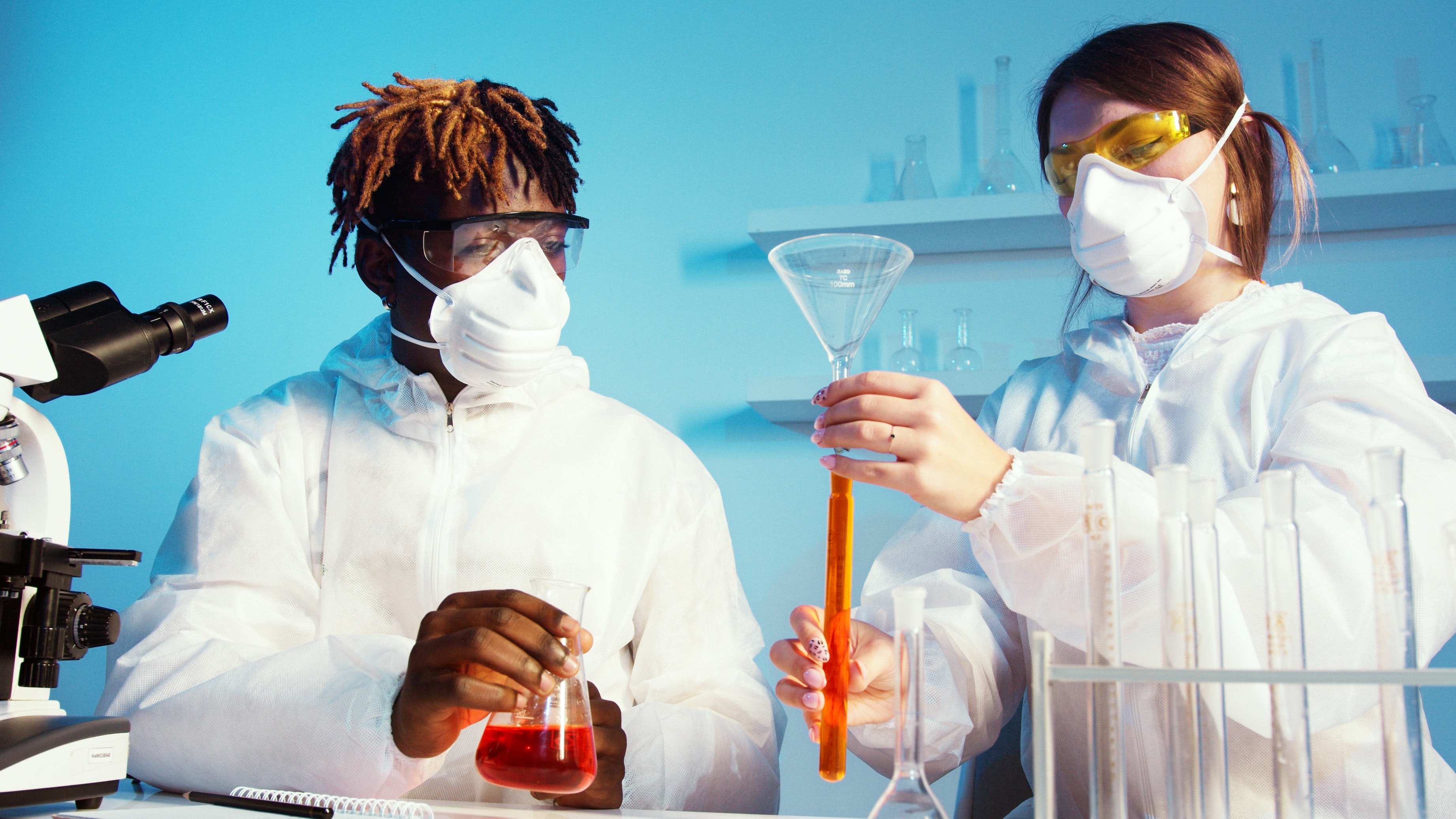 Male and female scientist conducting chemistry experiment.