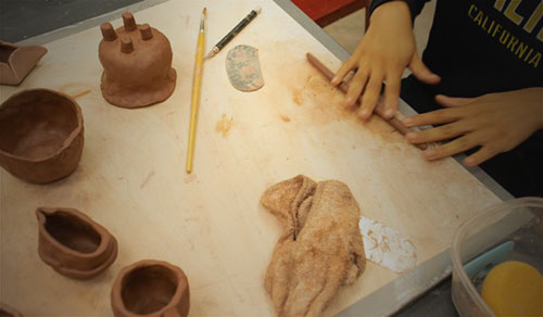 A studio-art student sculpts objects from clay