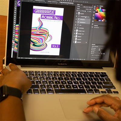 A graphic design student works with Photoshop on a laptop, manipulating an artistic image of a coffee cup