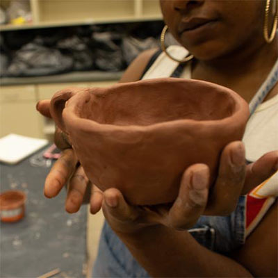 A studio art student shows a piece of clay pottery in progress