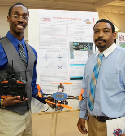 AAMU Student with drone in hand infront of poster presentation with professor